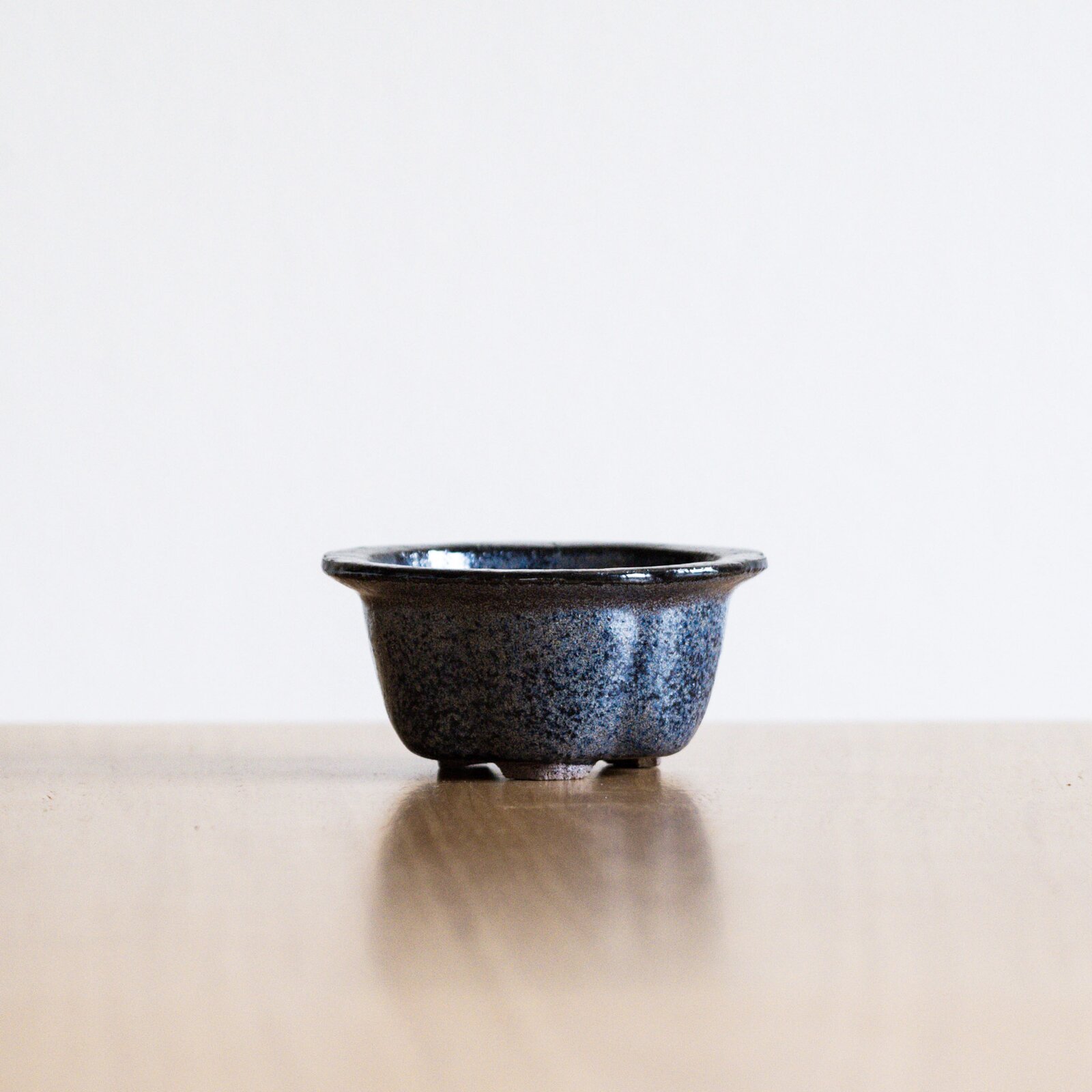 A handmade ceramic bonsai pot with a carved textured surface